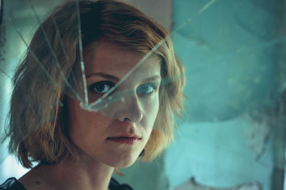 Woman looking through dirty broken glass closeup