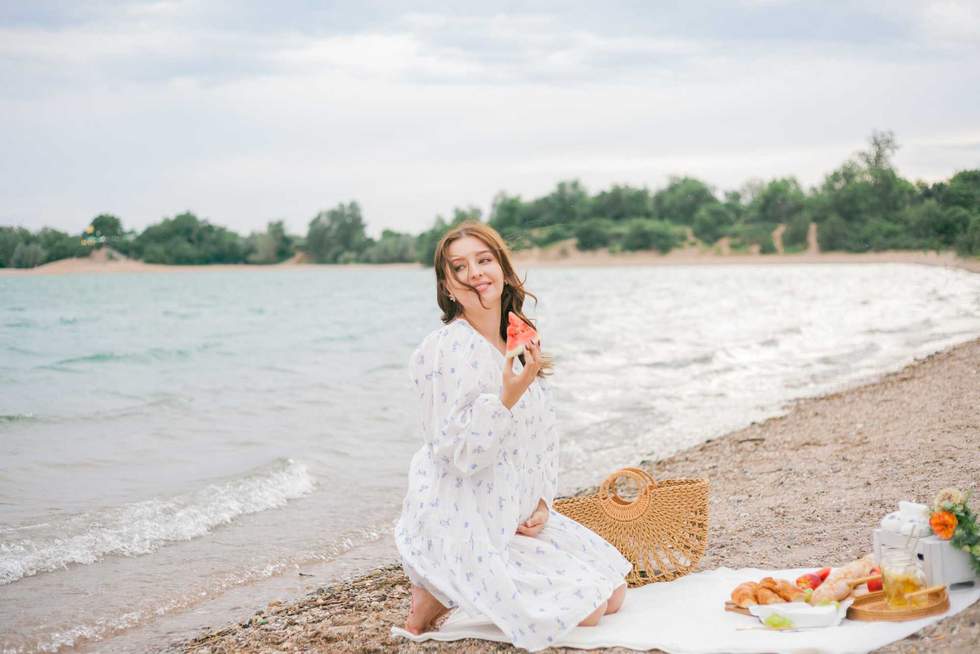 Young beautiful pregnant woman in a beautiful dress near the sea. Picnic. Watermelon. Summer.
