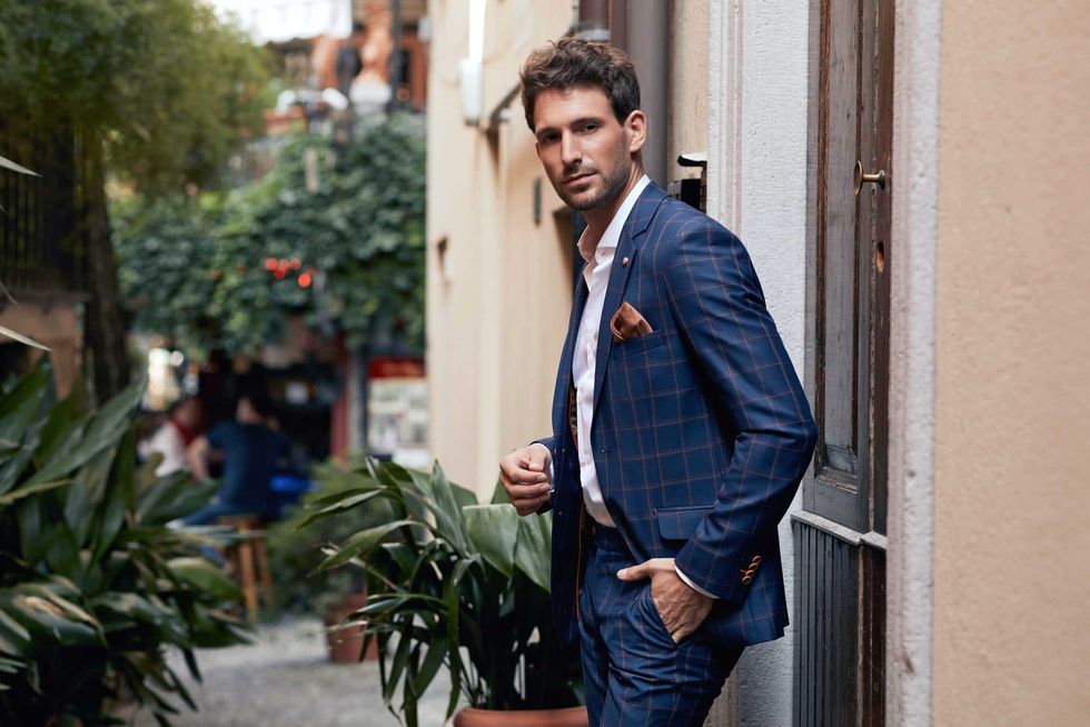 Young handsome man in classic checked suit standing on the street