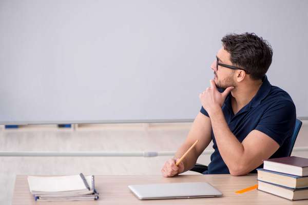 Young male teacher sitting in the classroom