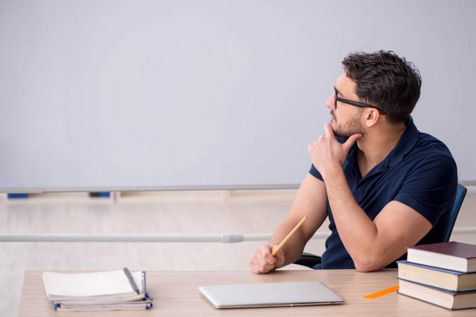 Young male teacher sitting in the classroom