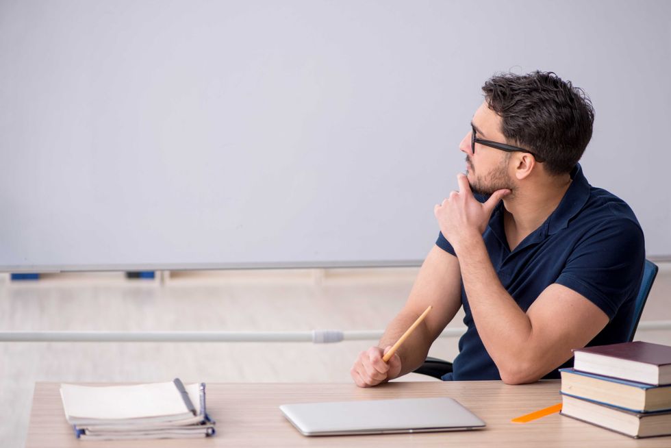 Young male teacher sitting in the classroom