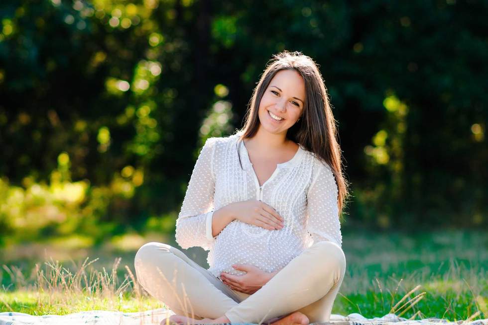 Young pregnant woman relaxing in park outdoors, healthy pregnancy