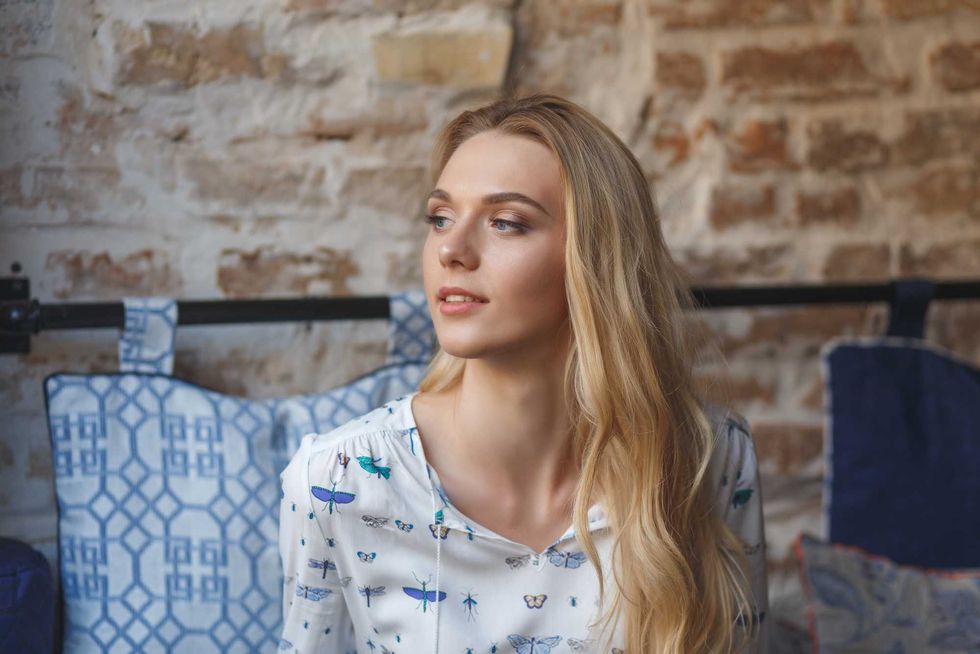 Young pretty woman wearing in white blouse resting on sofa in cafe