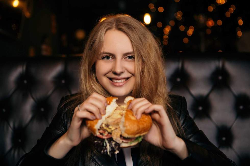 young woman eating a burger in a restaurant