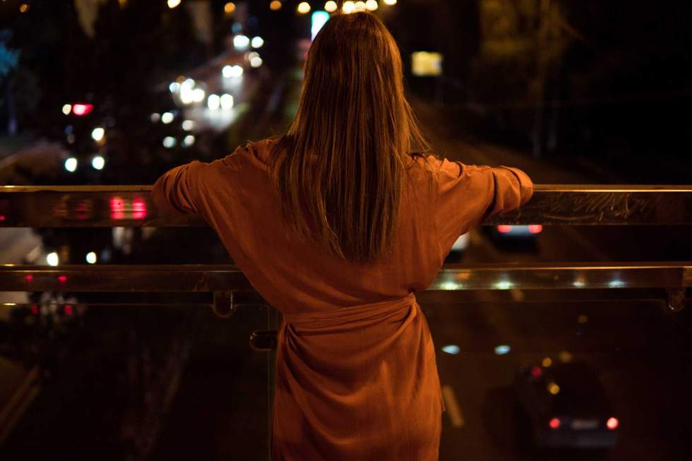 Young woman watching the view night city road from bridge.
