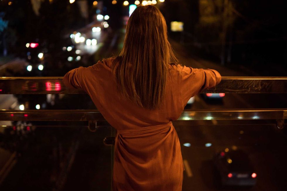 Young woman watching the view night city road from bridge.