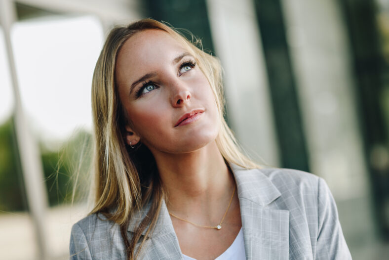 Blond girl wearing casual clothes in the street. Female with blue eyes. Beautiful young caucasian woman in urban background.