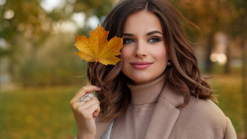 Happy autumn woman with fall yellow maple leaf portrait. Beautiful model with curly hairstyle .