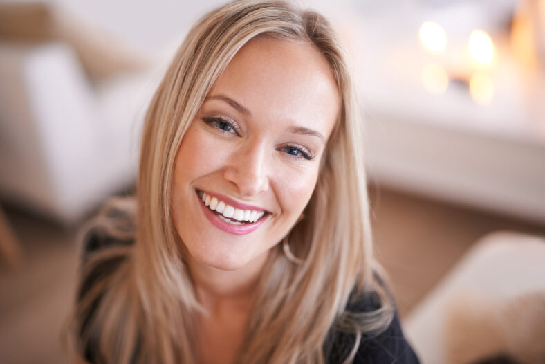 Woman, smile and portrait for relax and happy in home or indoor on weekend and alone on break and joyful. Young person and attractive for peace, rest or chill in living room or house on sofa.