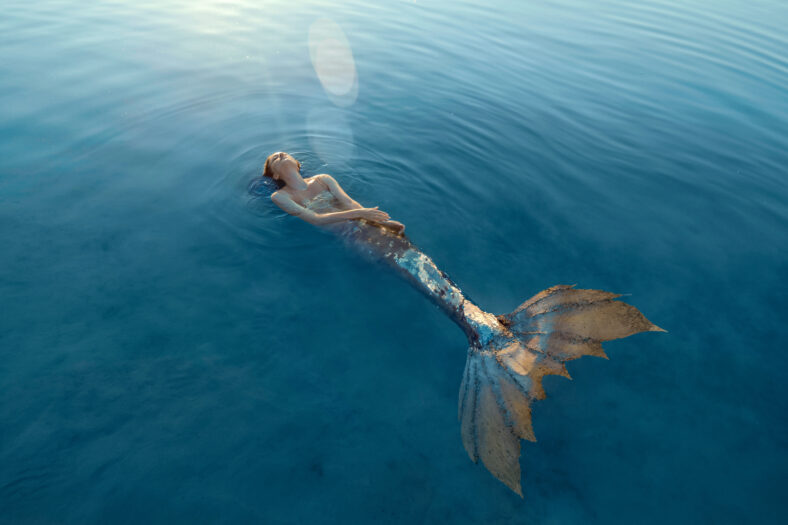 Beautiful redhead woman as mermaid with giant seashell