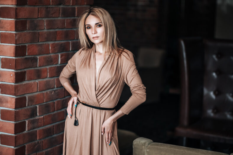 A beautiful girl in an evening dress on the background of a dark stone wall.