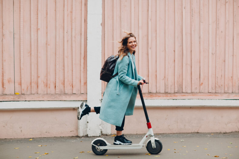 Young woman with electric scooter at the city.