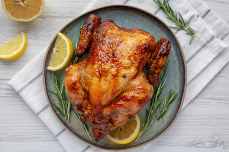 Homemade Lemon and Herb Rotisserie Chicken on a Plate, top view. Flat lay, overhead, from above. Close-up.