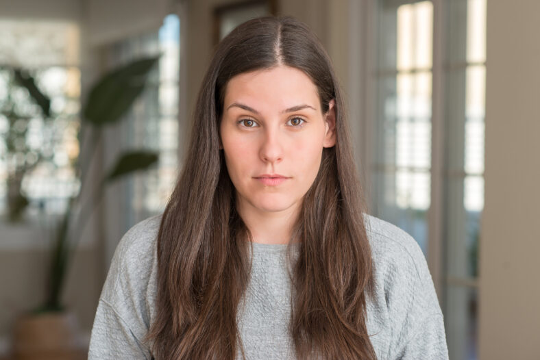 Young beautiful woman at home with serious expression on face. Simple and natural looking at the camera.
