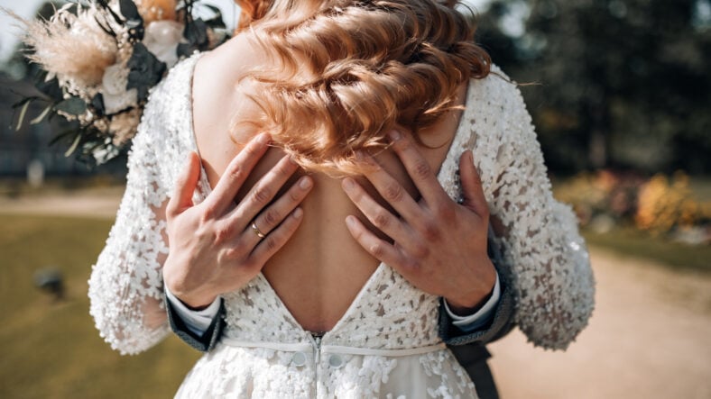 Groom hugs bride with his hands on her back