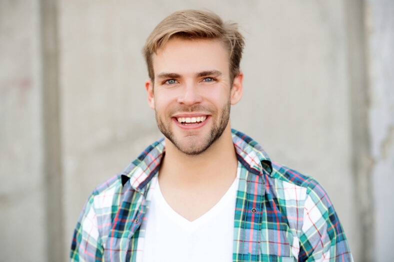 Portrait of happy man in casual style shirt. Stylish face portrait of unshaven guy. Handsome young man outdoor. Millennial man wearing checkered shirt. Casual style of millennial man.