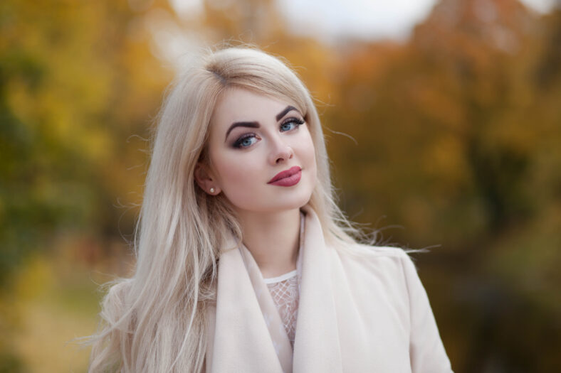 elegant young woman walking in autumn park