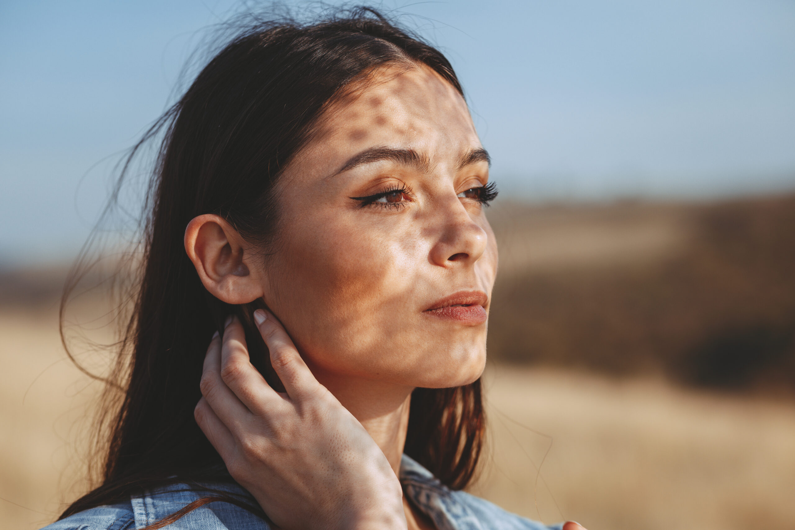 Portrait of a young woman with shadows texture on the face in a meadow with