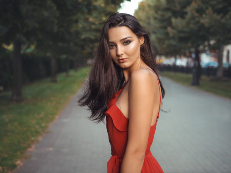 Outdoor photo of attractive brunette model in red dress