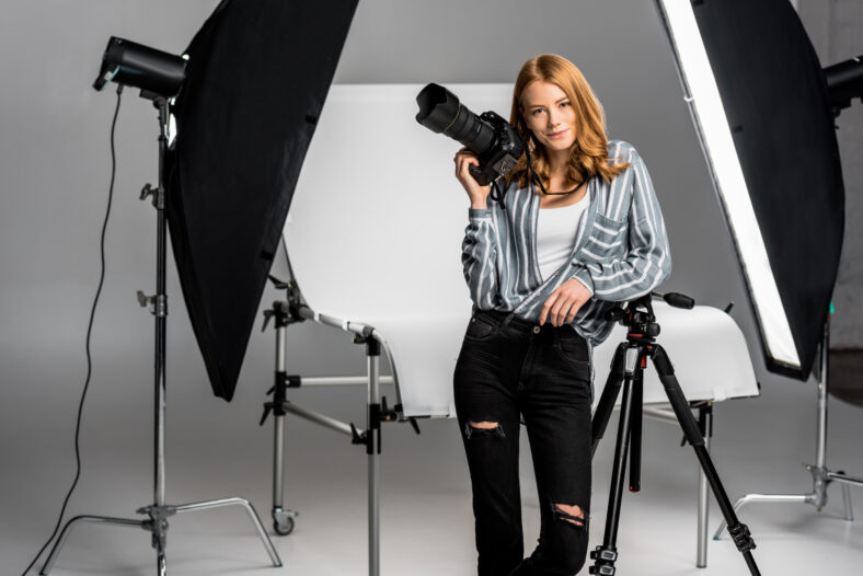 attractive young female photographer working in professional photo studio