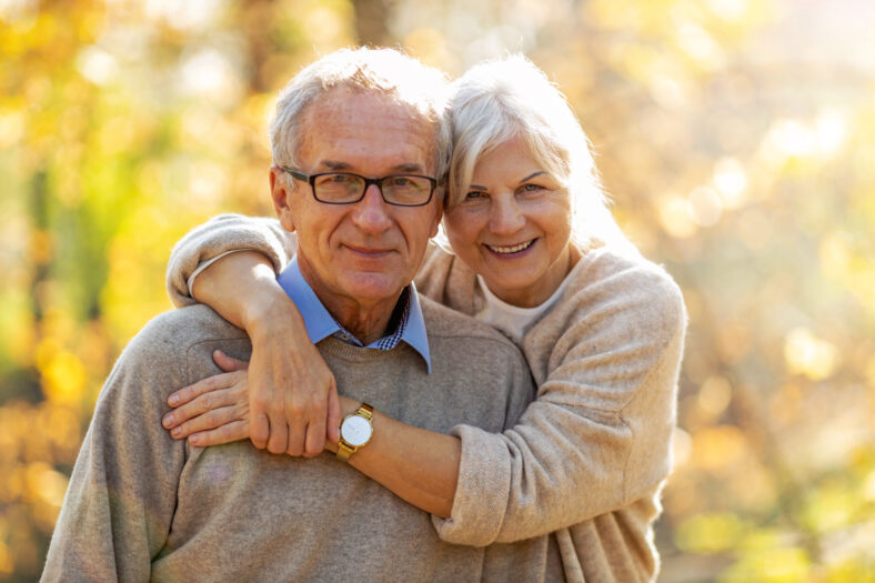 Elderly couple embracing in autumn park