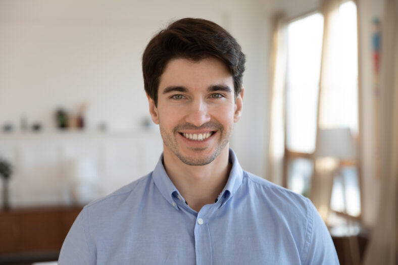 Close up headshot portrait of smiling young caucasian man stand look at camera posing, happy excited millennial male renter or tenant feel positive optimistic about new life, beginning concept