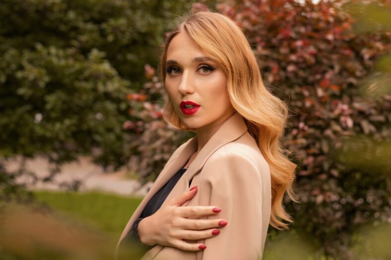 Portrait of young woman with long blonde hair outdoor in autumn park