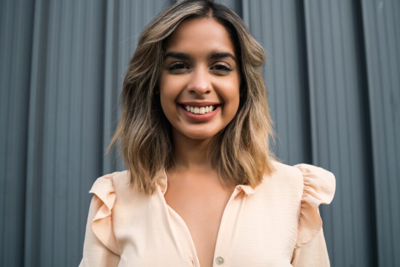 Close-up of young woman smiling while standing outdoors on the street. Urban concept.
