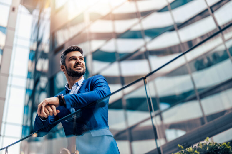 Handsome businessman portrait outdoor. He is standing in front of modern building.