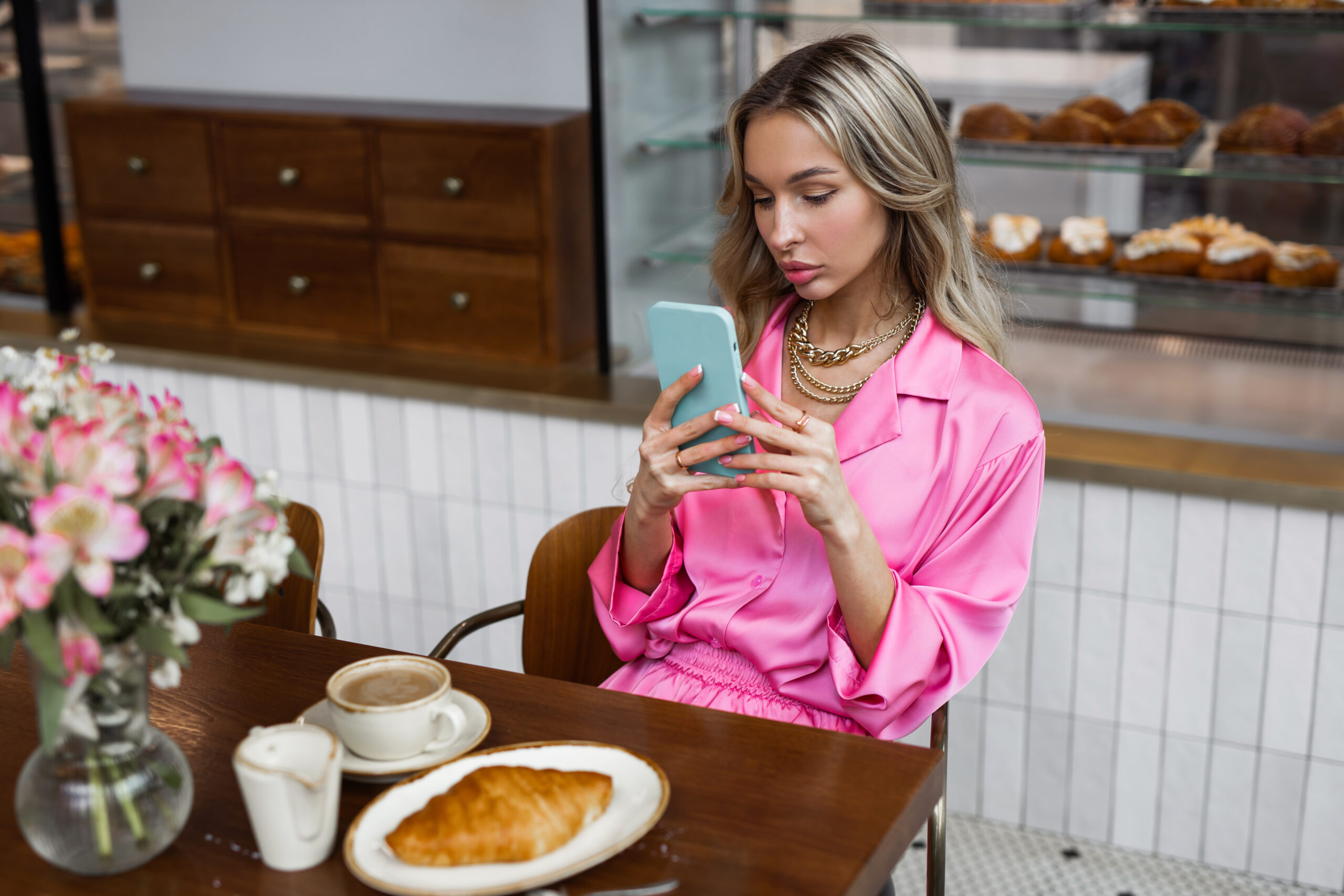 woman sitting at a cafe table texting