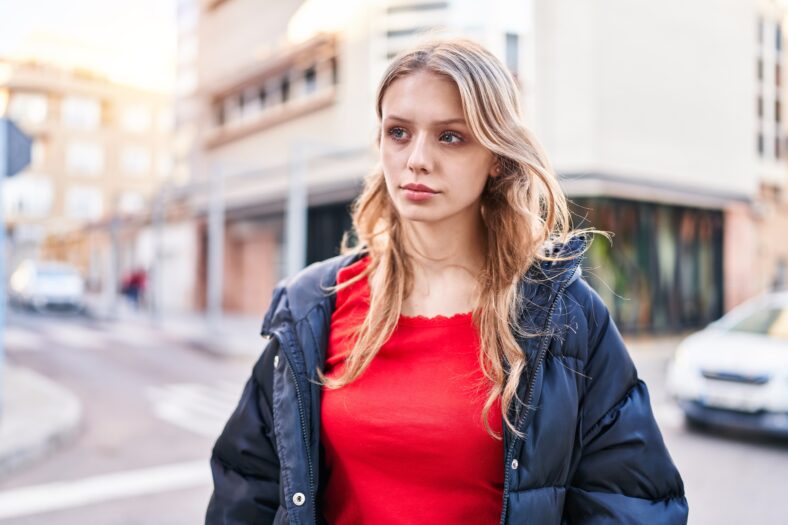 Young blonde woman looking to the side with serious expression at street