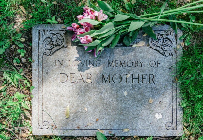 Grave marker in cemetery with flowers for concept of death and loss