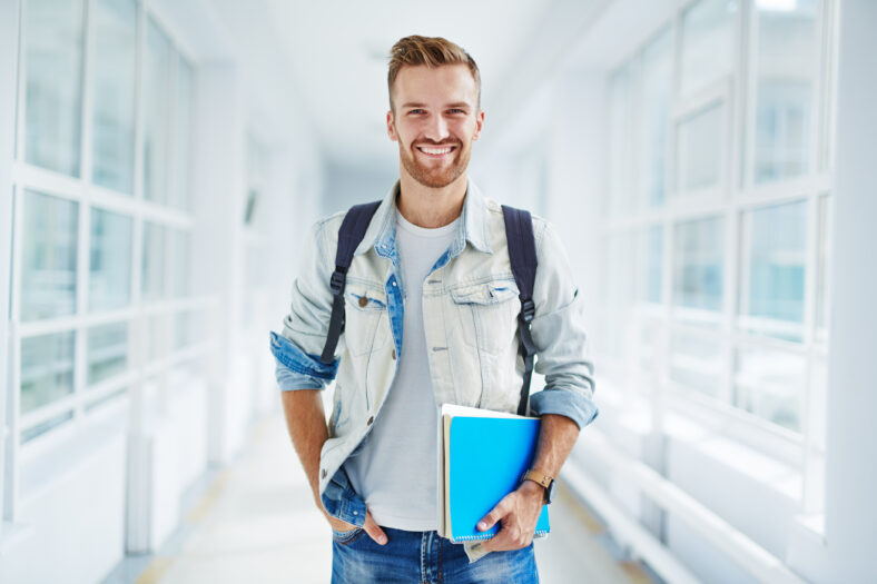 Clever student with books looking at camera with smile