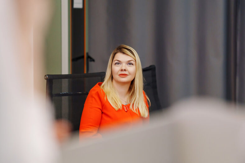 Attractive blonde woman in red dress listening to speaker at conference. organization of speeches for training and at seminars.