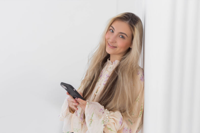 cute young woman with loose hair holding phone in hands