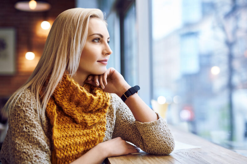 thoughtful young woman looking through window in a cafe during winter day