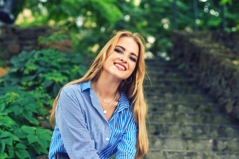 Attractive young girl resting in the city Park . Beautiful fashionable woman in summer outdoors . Women's beauty and fashion concept