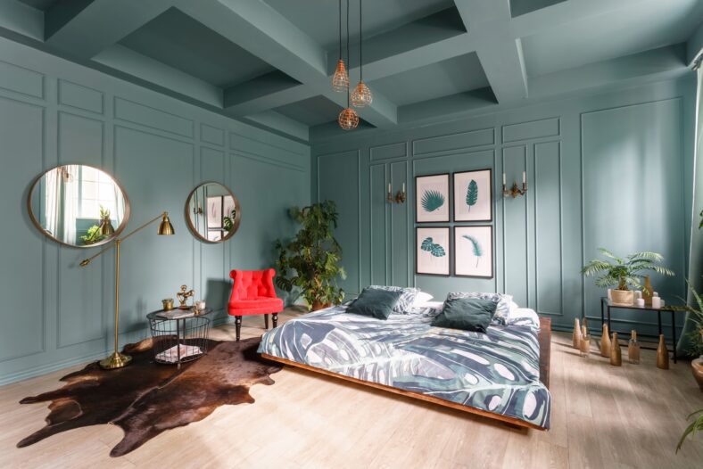Morning interior in bedroom hotel. Bright and clean interior design of a modern room with bed, chair and houseplant. Mirrors on walls.