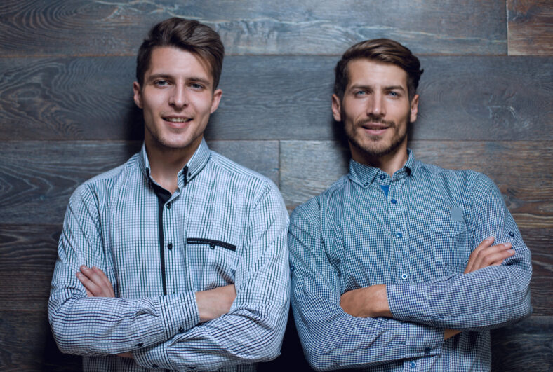 Two brutal mans isolated on grey background. Crosed arms.