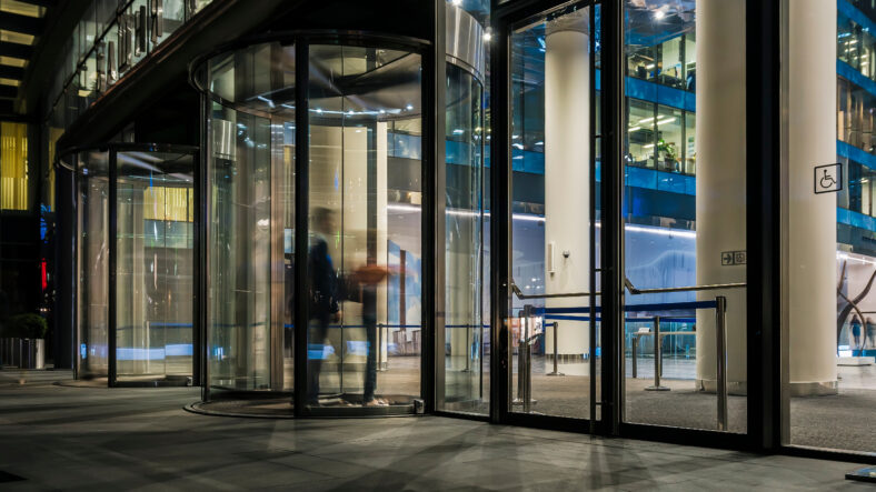 the flow of people passing through the revolving door of the modern office building at the end of the working day