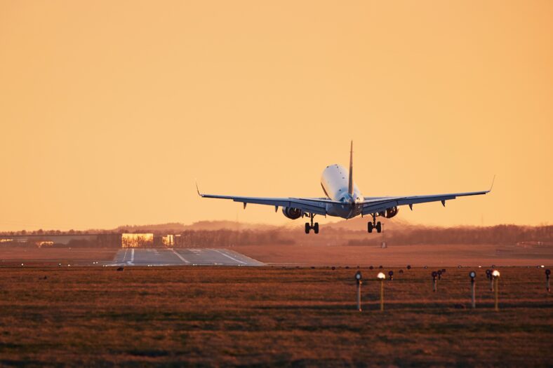 Traffic at airport. Airplane landing on runway at sunset.