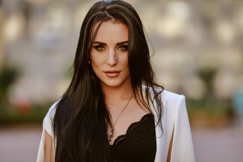 beautiful brunette woman with long hair in a white suit and lace top