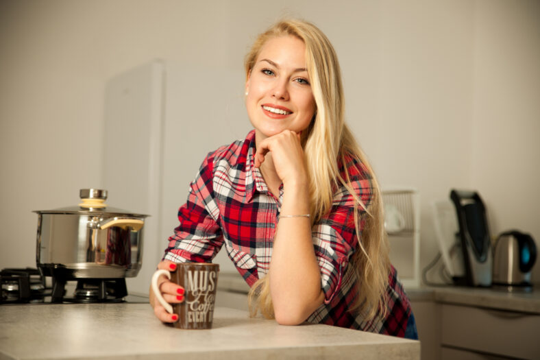 Beautiful young woman drinks coffee in the kitchen.