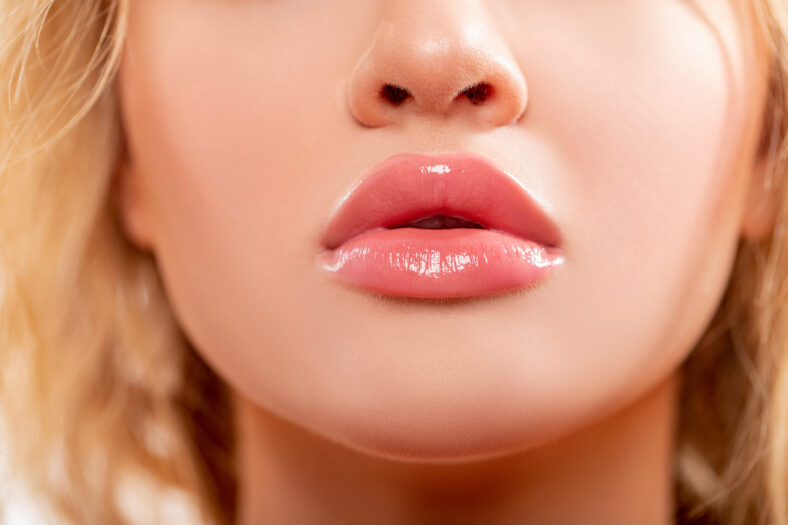 Lips. Beauty injections concept. Close up view of beautiful woman lips with Peachy lipstick. Fashion make up. Cosmetology, drugstore or fashion makeup. Studio shot. Perfect sexy Lips.