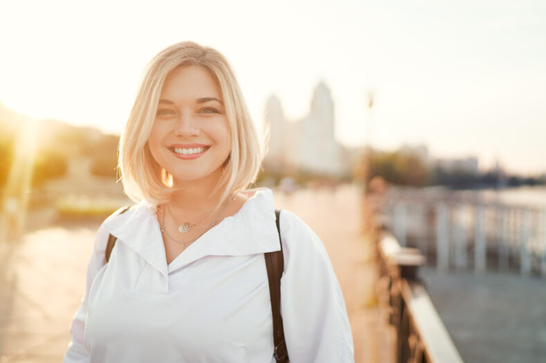 Outdoor portrait of happy young woman on city promenade.