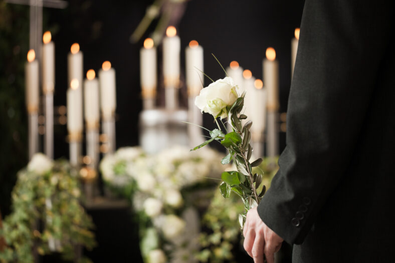 man at funeral with white rose mourning the dead