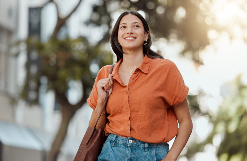 Stylish, happy and trendy student walking in a city, commuting to a college and enjoying a weekend break downtown. Smiling, edgy or funky woman exploring, visiting and enjoying town while sightseeing.