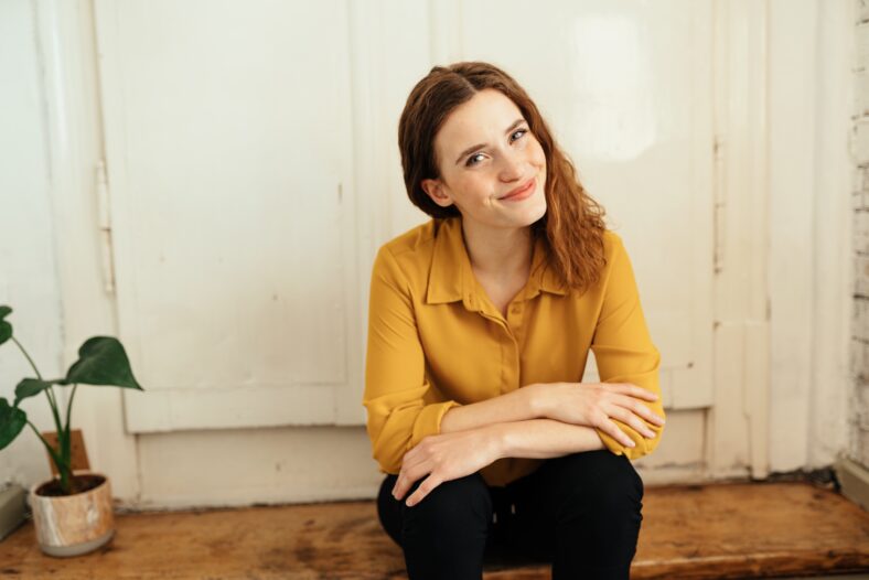 Young woman sitting on wooden stairs and looking cheekily at camera
