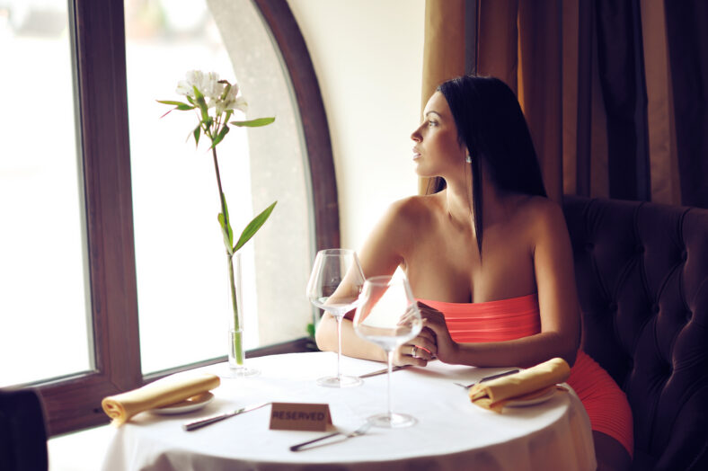Hermosa mujer joven sentada a la mesa sola en un restaurante